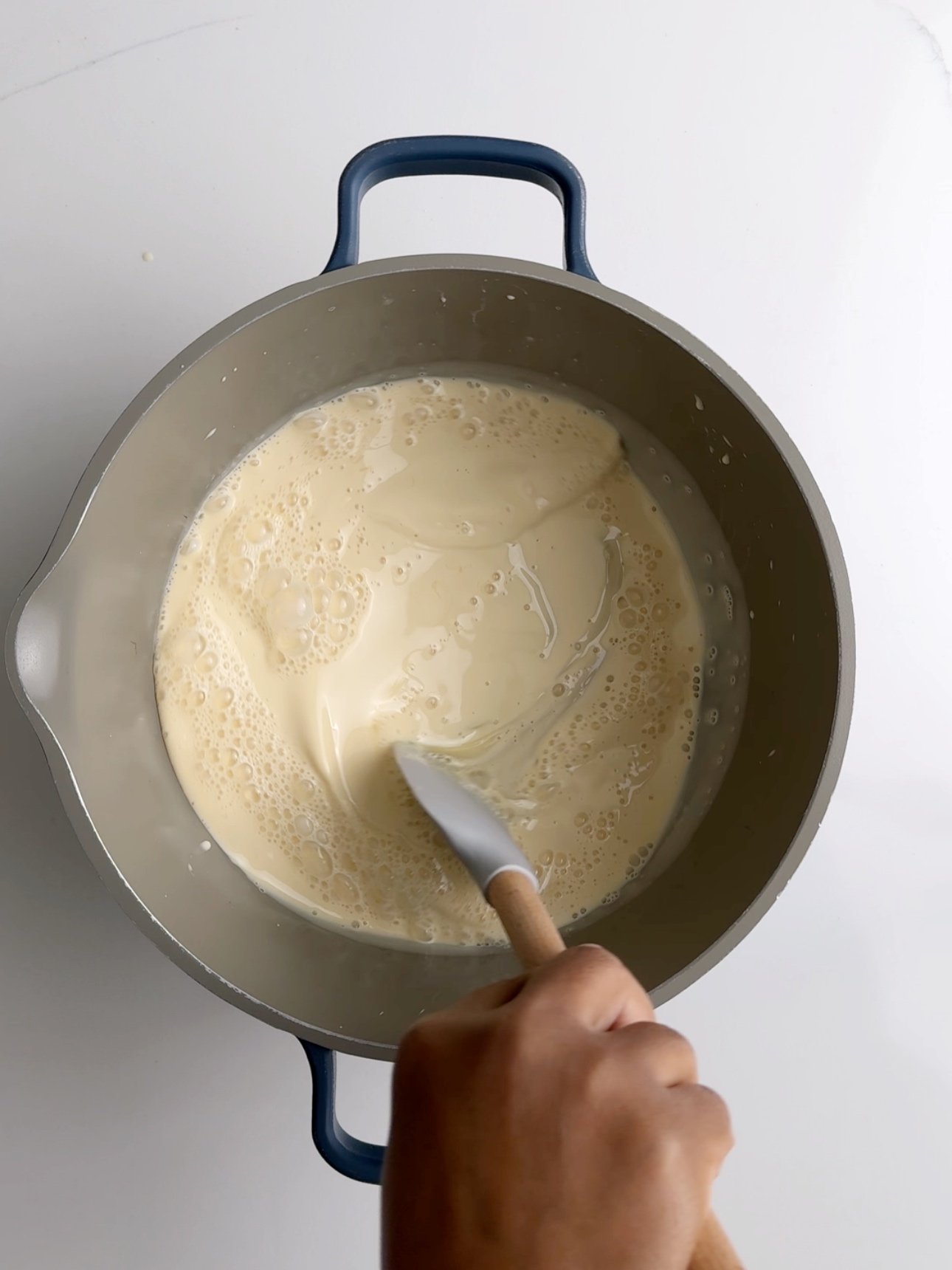 Mixing condensed milk and evaporated milk together in a grey saucepan