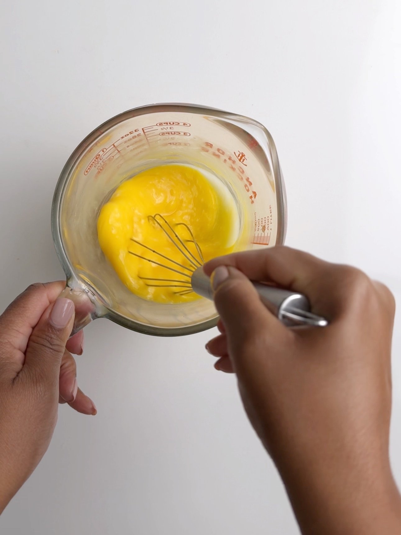 Whisking eggs in a measuring cup. The measuring cup is a pyrex glass cup with red writing