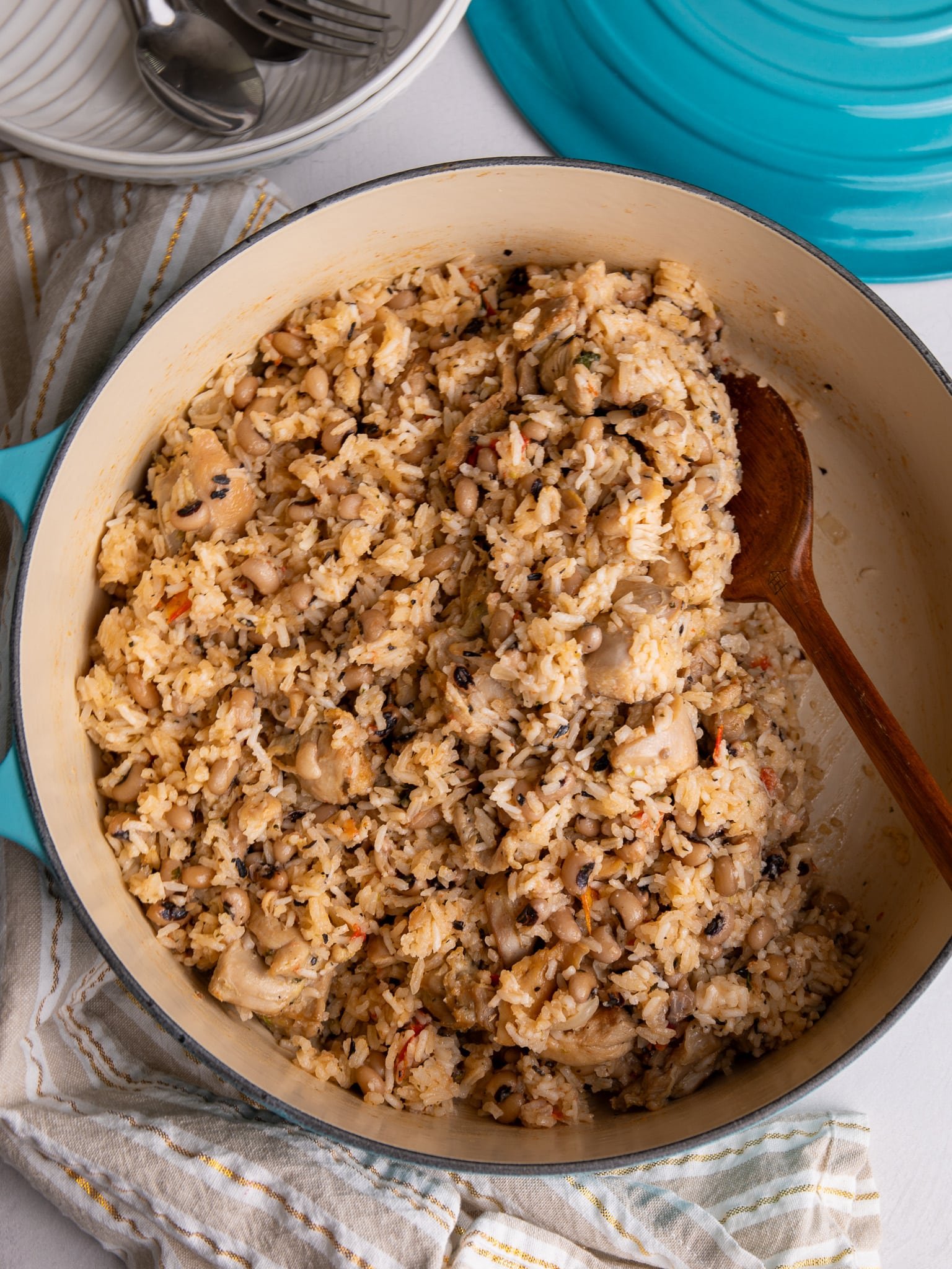 Overhead view of finished chicken cook-up rice in a Dutch oven with a wooden spoon.