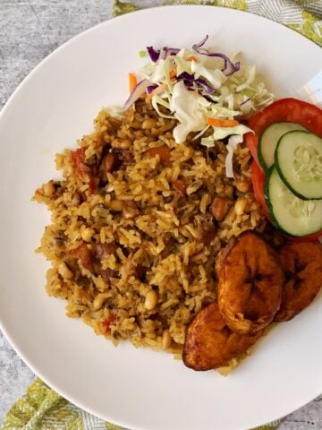 Cookup rice and plantain and salad on a white plate