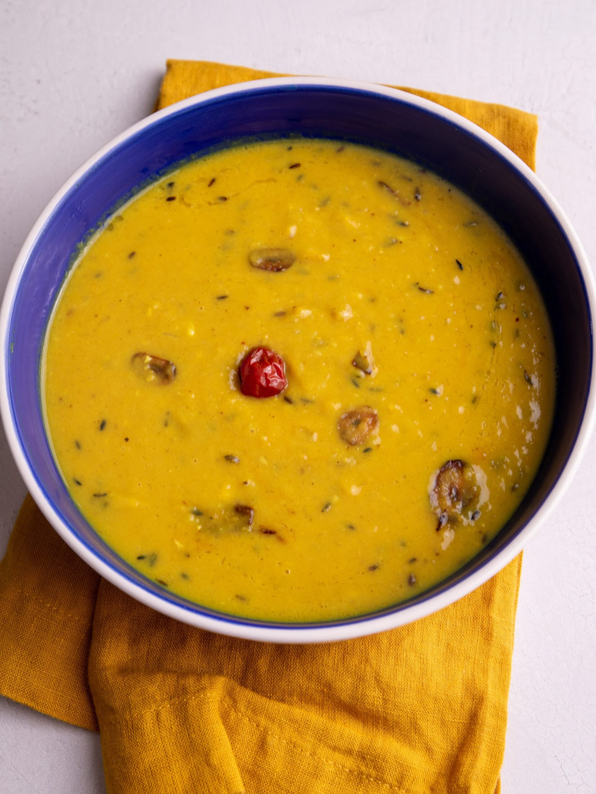 Guyanese dhal in a blue bowl on a mustard colored napkin.