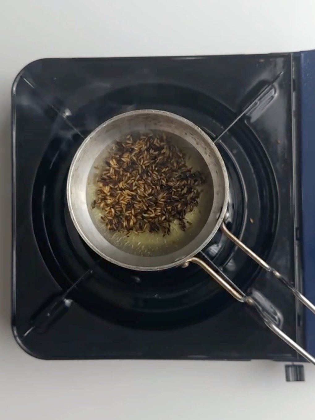 Cumin (geera) and oil in a tadka pan waiting to be chunkayed Guyanese dhal