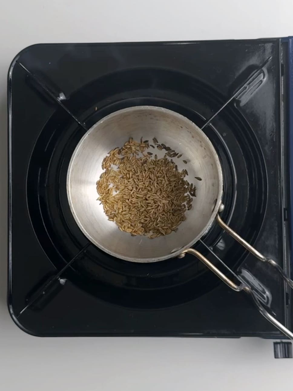 Toasting whole cumin seeds in a tadka pan over a flame to make Guyanese dhal