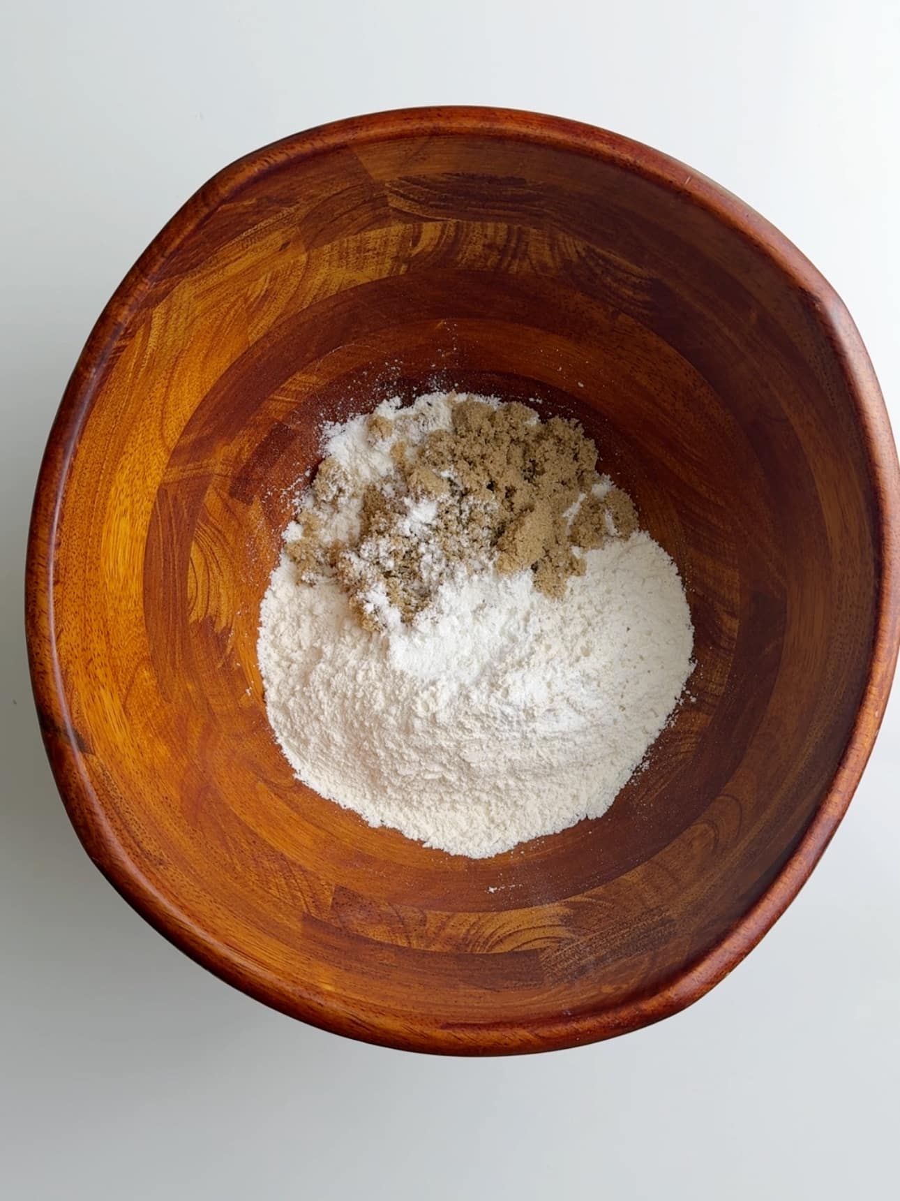 All purpose flour, sugar, baking powder and salt in wooden bowl on a white counter