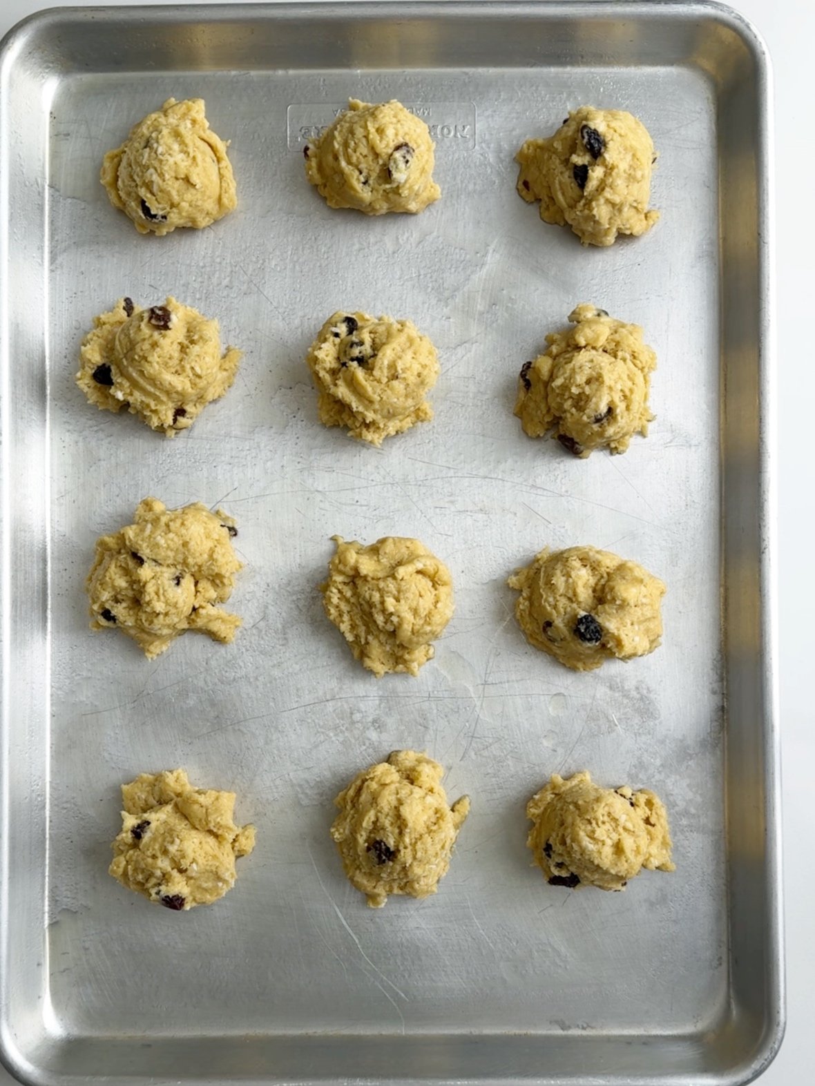 12 coconut buns scooped out on a greased cookie sheet