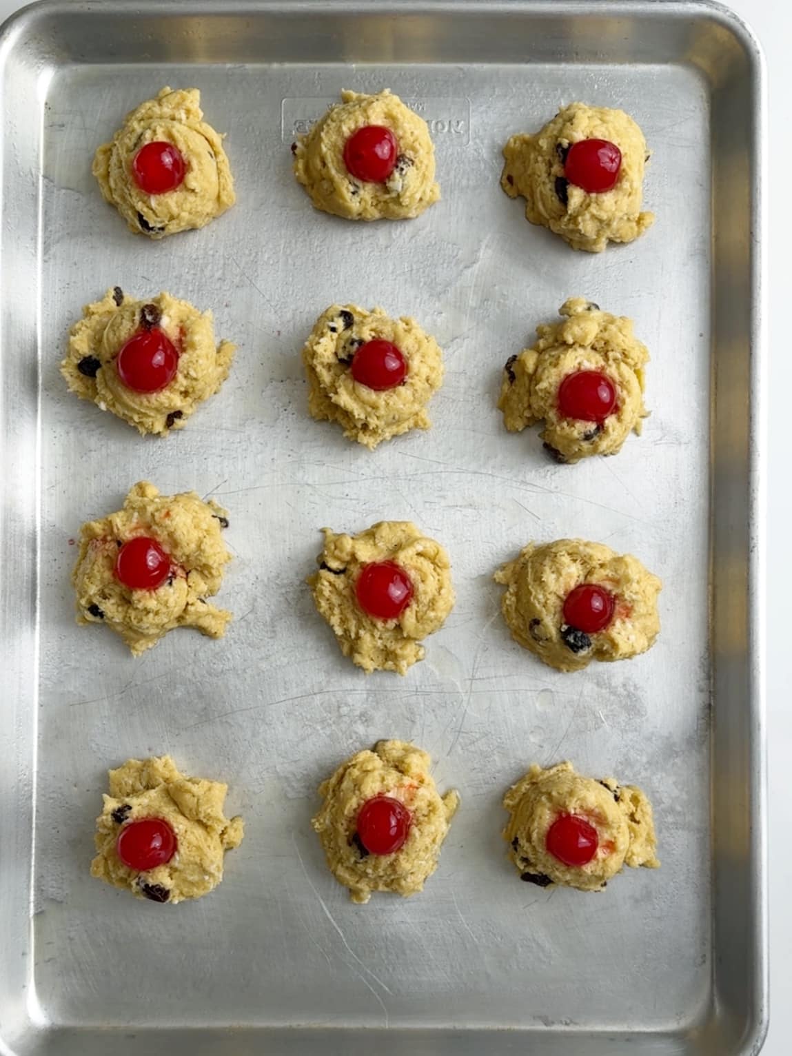 Buns with maraschino cherries on top ready for the oven.