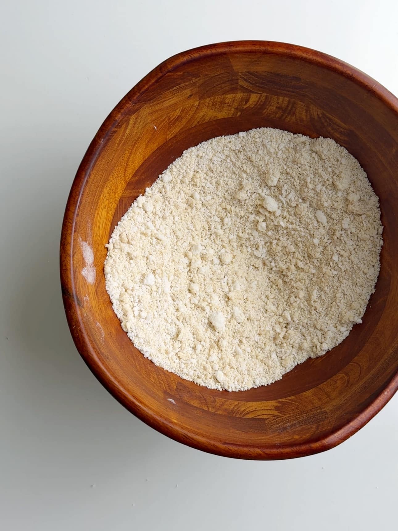 Dry ingredients in a wooden bowl on a white coutner