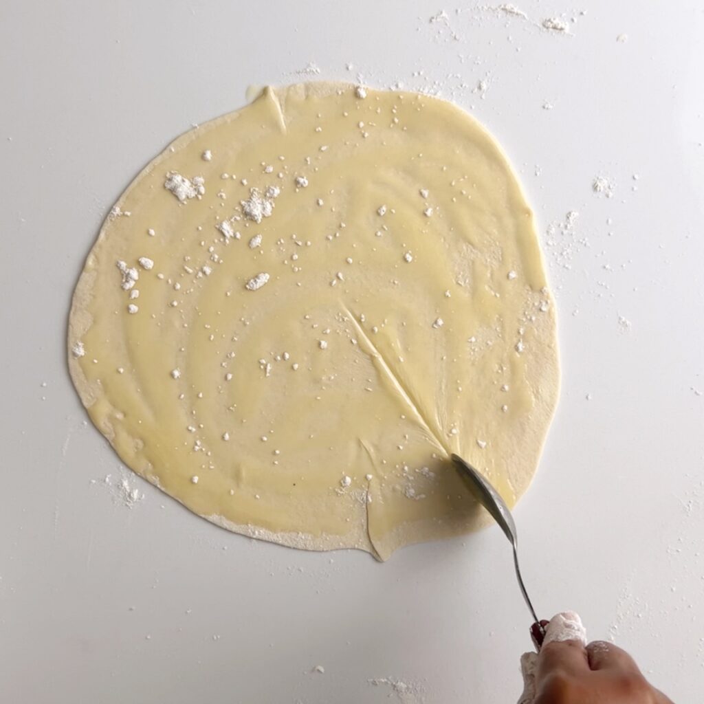 Cut a slit into the flat round dough disk with oil and a sprinkle of flour.