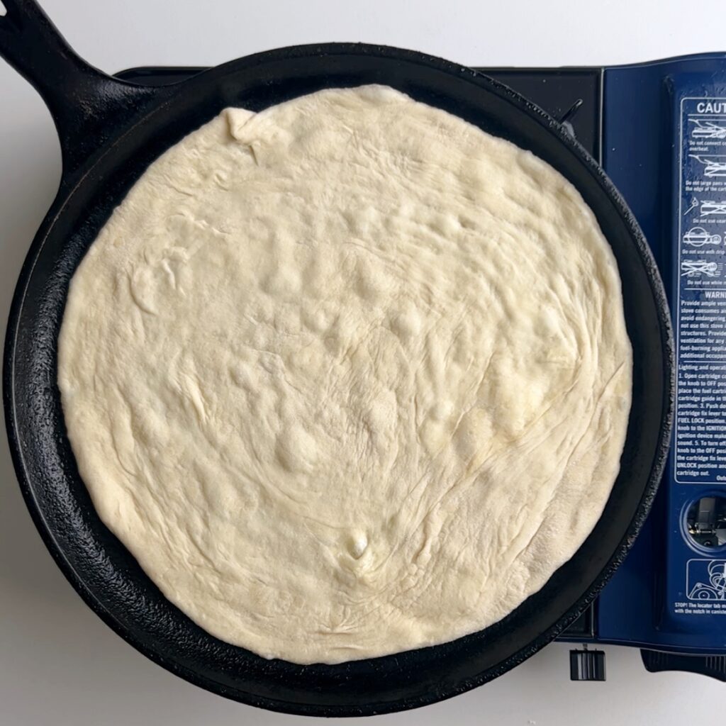 Rolled out roti on a hot skillet with small air bubbles starting to form