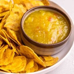 Close up of Guyanese mango sour served with plantain chips and cassava chips on a white plate.