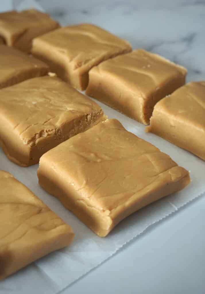 Squares of vanilla fudge separated on a piece of parchment