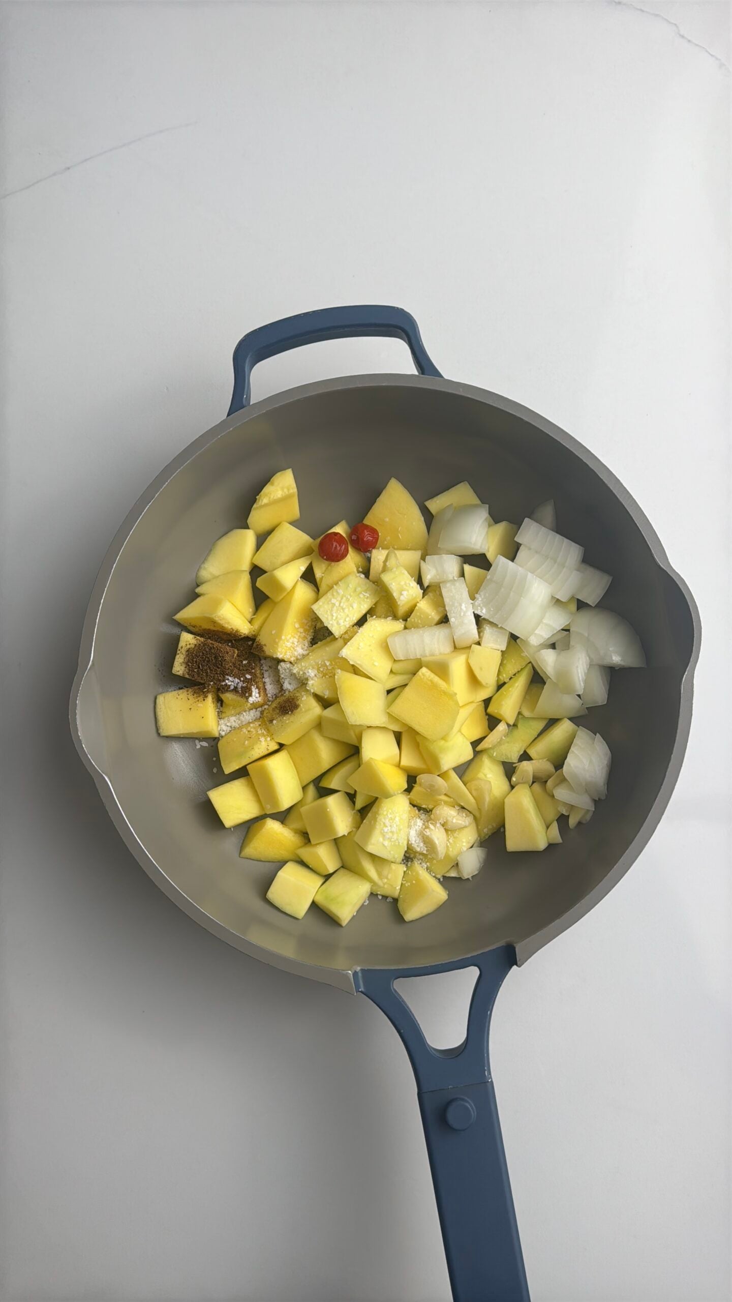 Green mangoes, onion, garlic, wiri wiri peppers, geera, and salt added to a saucepan before cooking Guyanese mango sour.