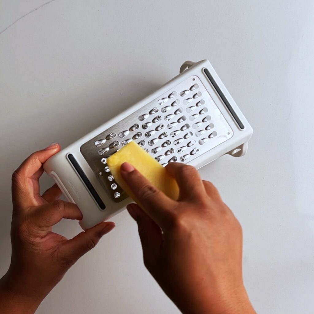 grating pineapple on a box grater