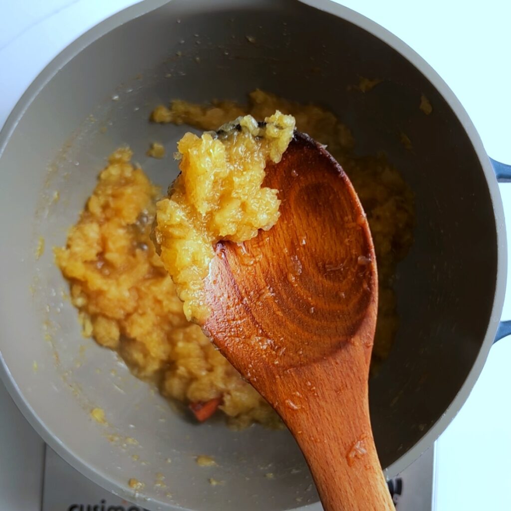 pineapple jam on a wooden spoon over a gray pot