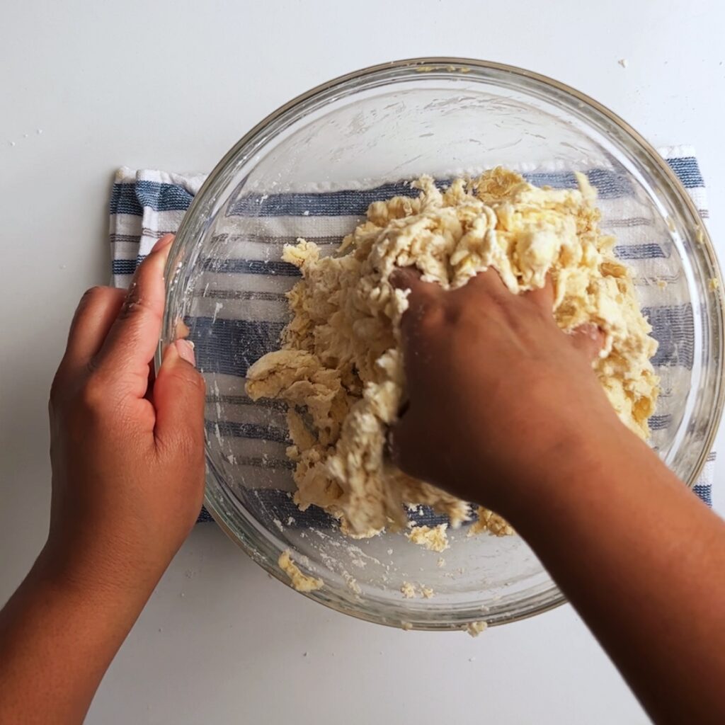 mixing pastry dough by hand in a glass bowl for Guyanese beef patties