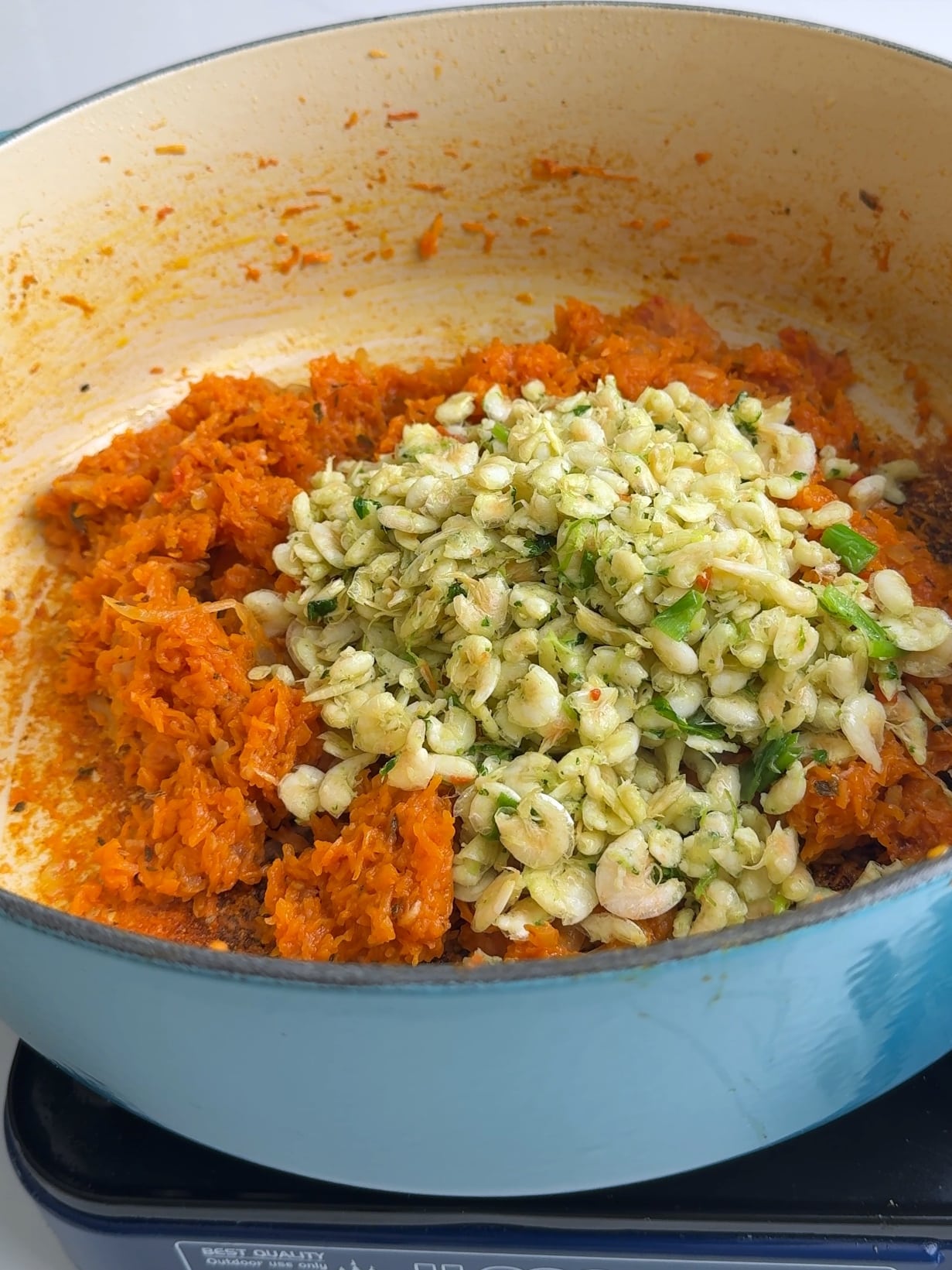 Adding seasoned Guyanese white belly shrimp to the pumpkin