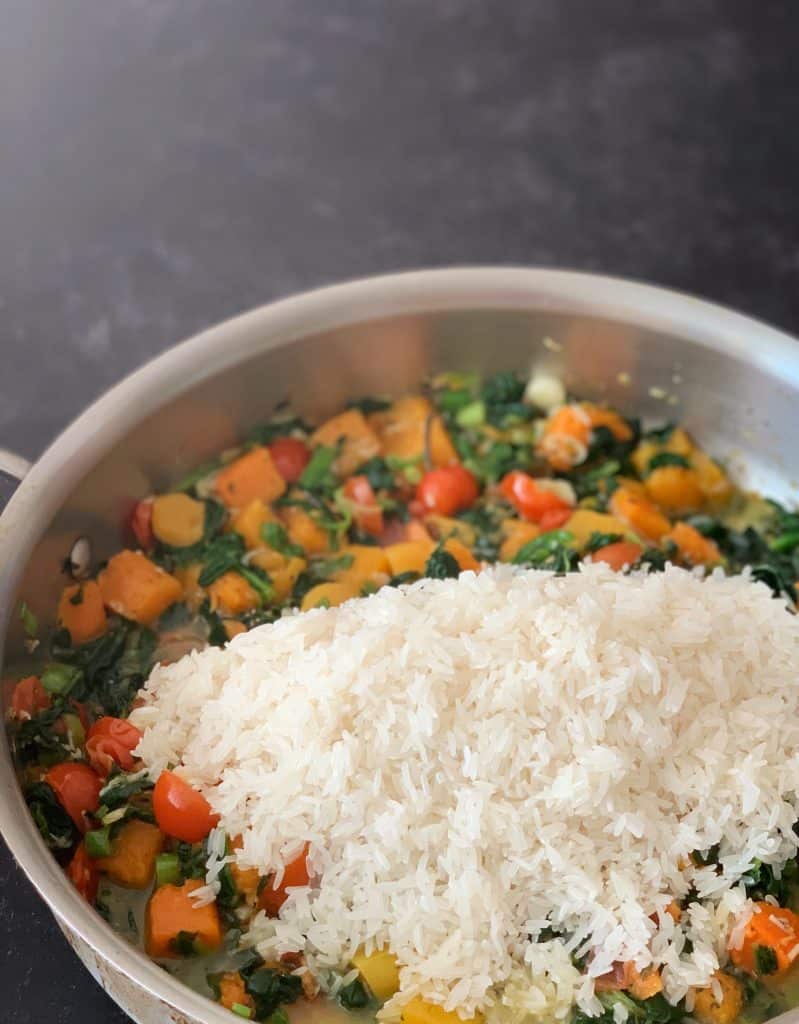 jasmine rice added to sautéed veggies in a skillet