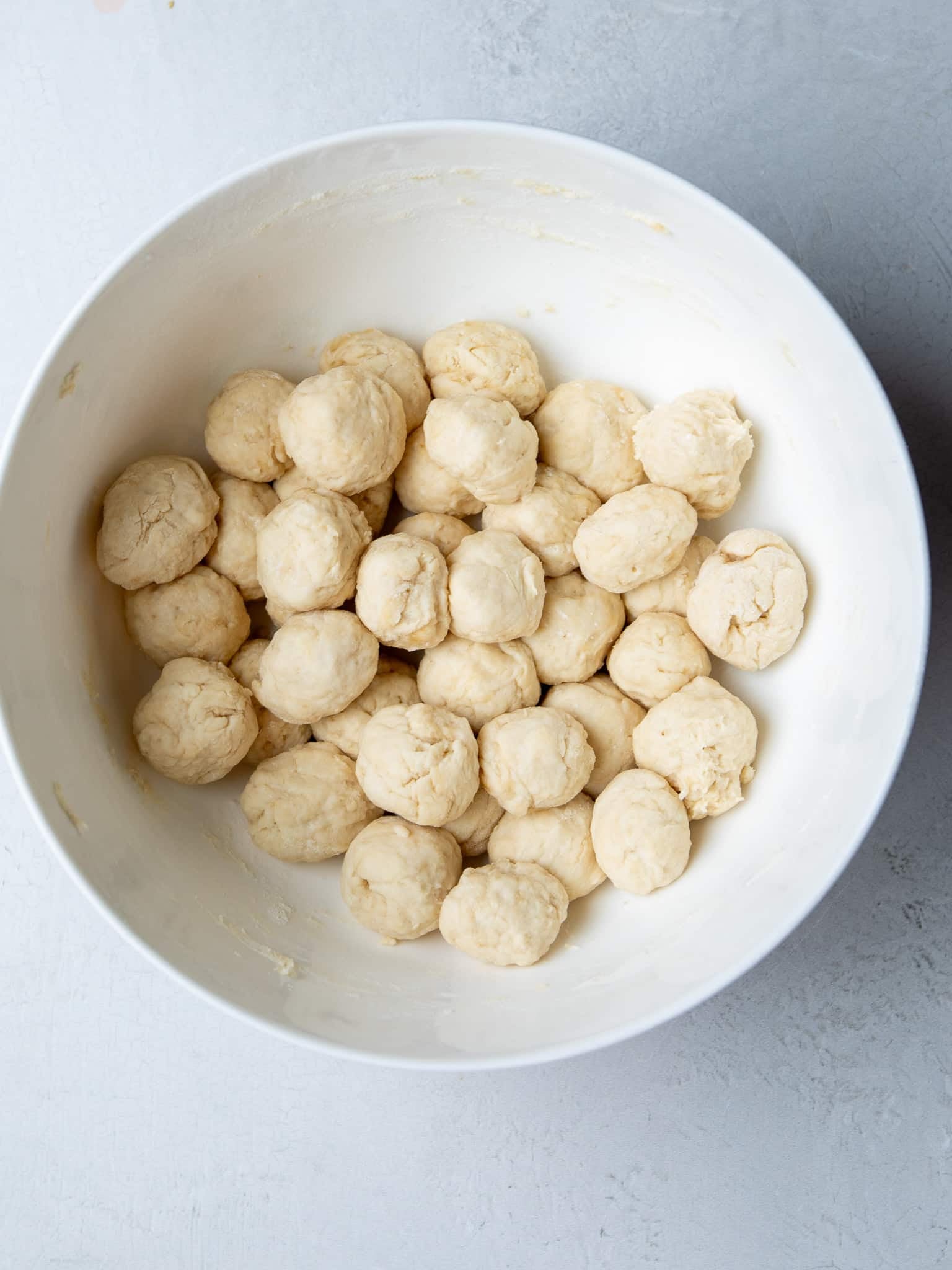 Tablespoon-size dumplings rolled and ready to cook in a white mixing bowl