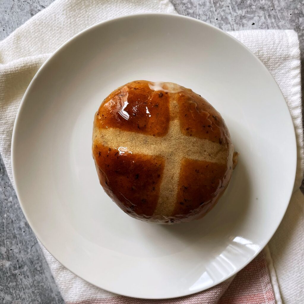 cross buns on a white plate on a blush and cream colored napkin