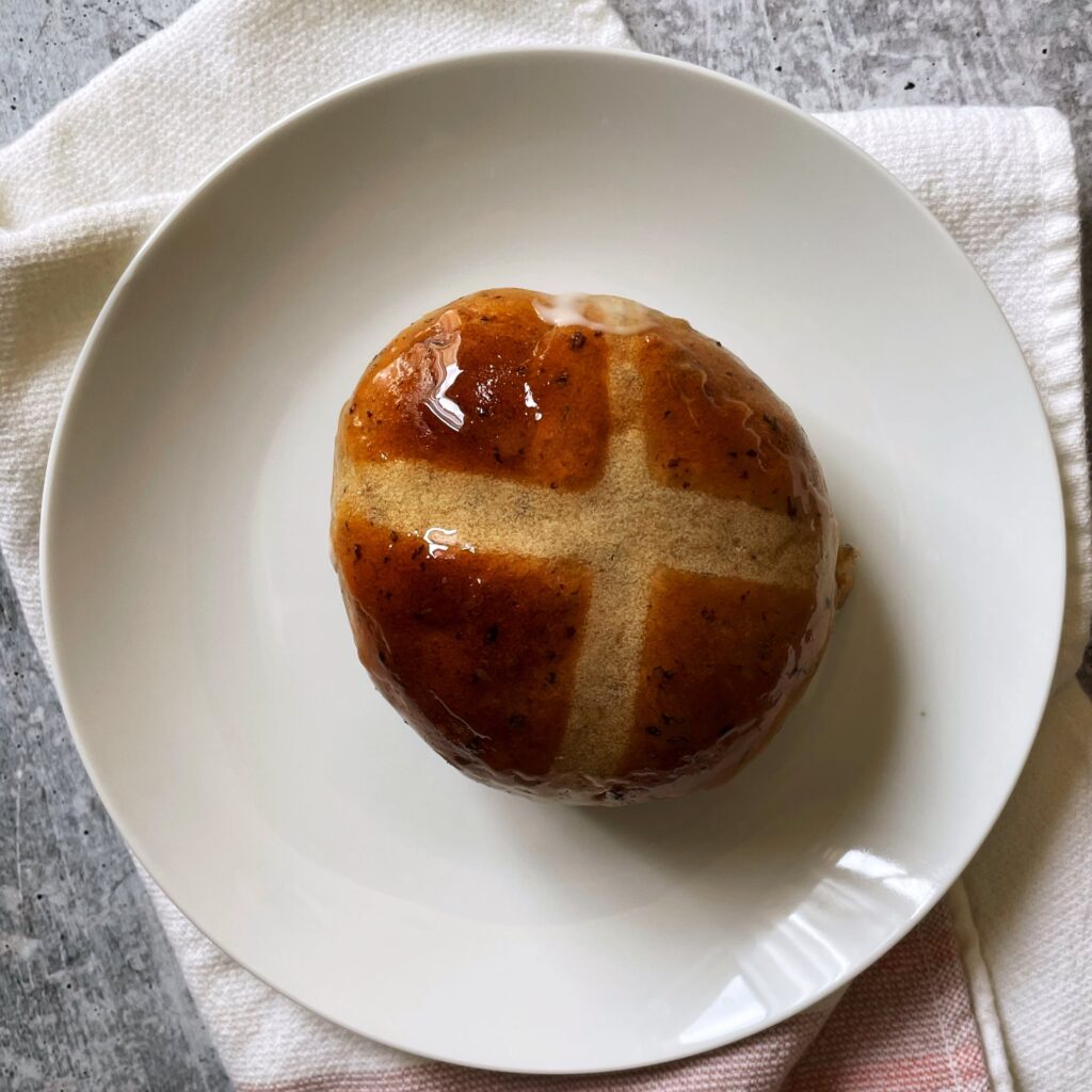 hot cross buns on a white plate on a blush and cream colored napkin