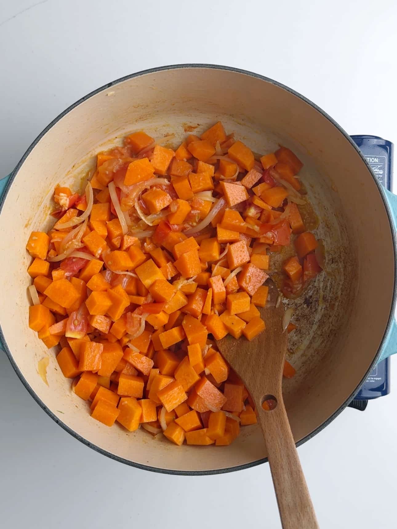 Pumpkin, tomatoes and onions cooking in a pot to make Guyanese pumpkin