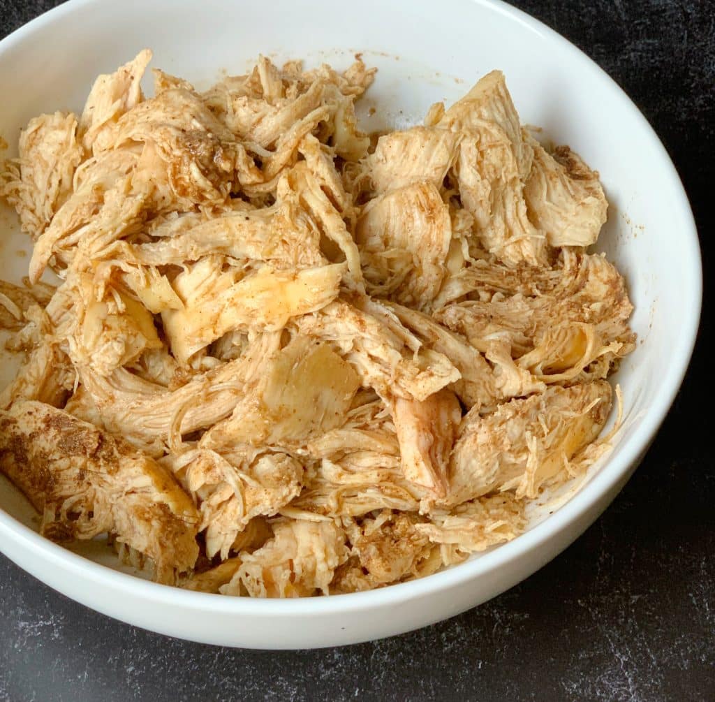 close up view of cooked, seasoned and shredded chicken in a bowl