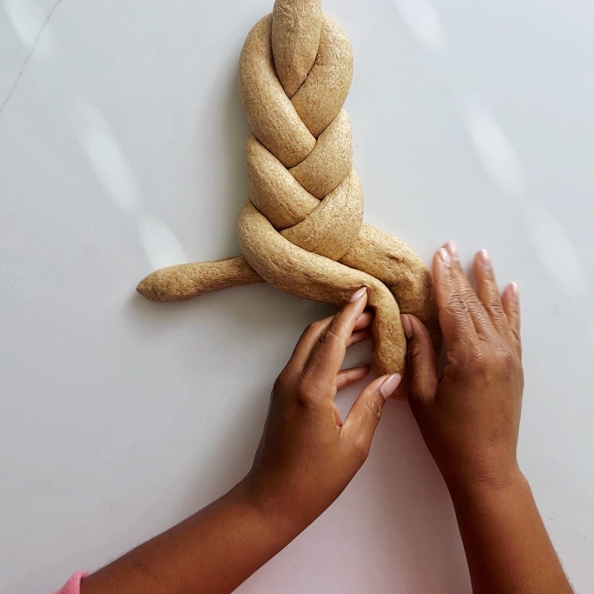 braiding the bread loaf on a white surface