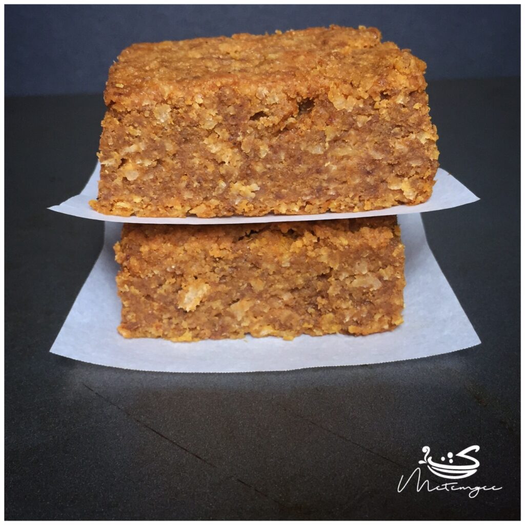 two slices of Guyanese cassava pone, stacked with parchment paper between each slice