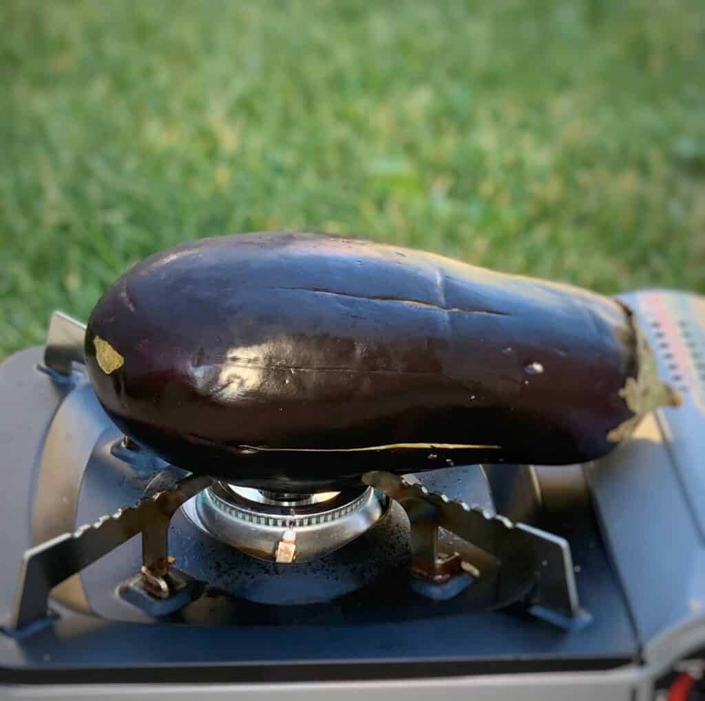 an eggplant positioned on a burner outside