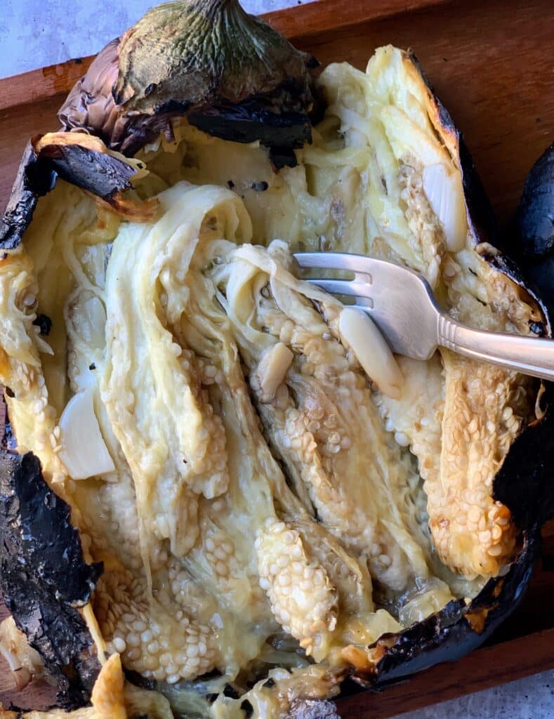 the flesh of a roasted eggplant with a fork inserted