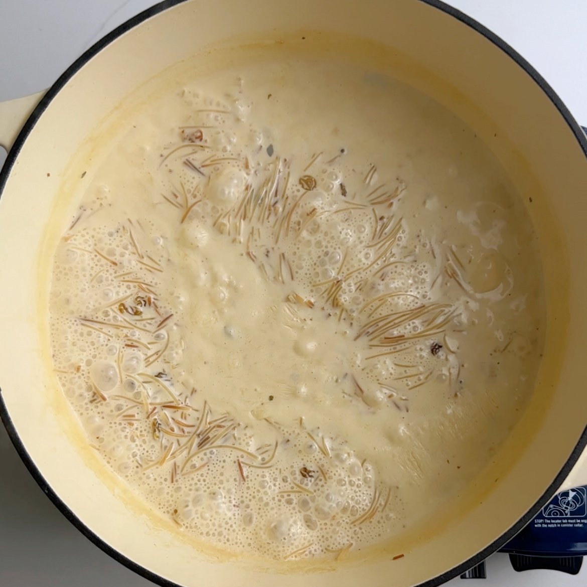 vermicelli noodles and milk boiling in a cream dutch oven