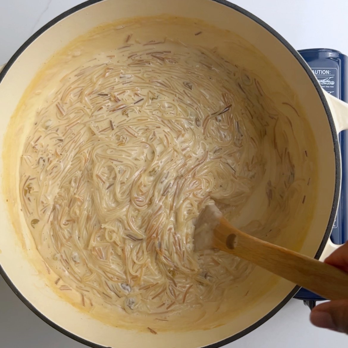 Mixing vermicelli noodles with a wooden spoon