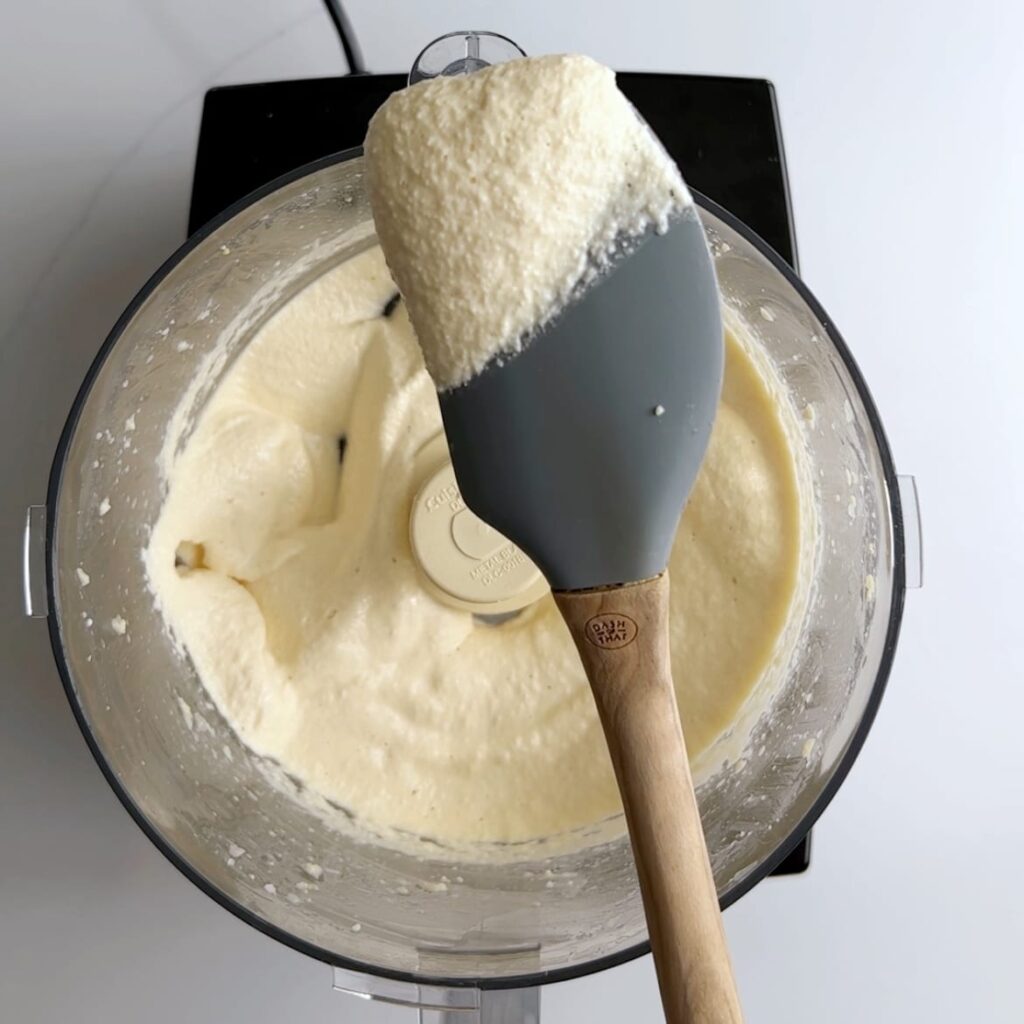 blended split peas on a rubber spatula over a food processor bowl