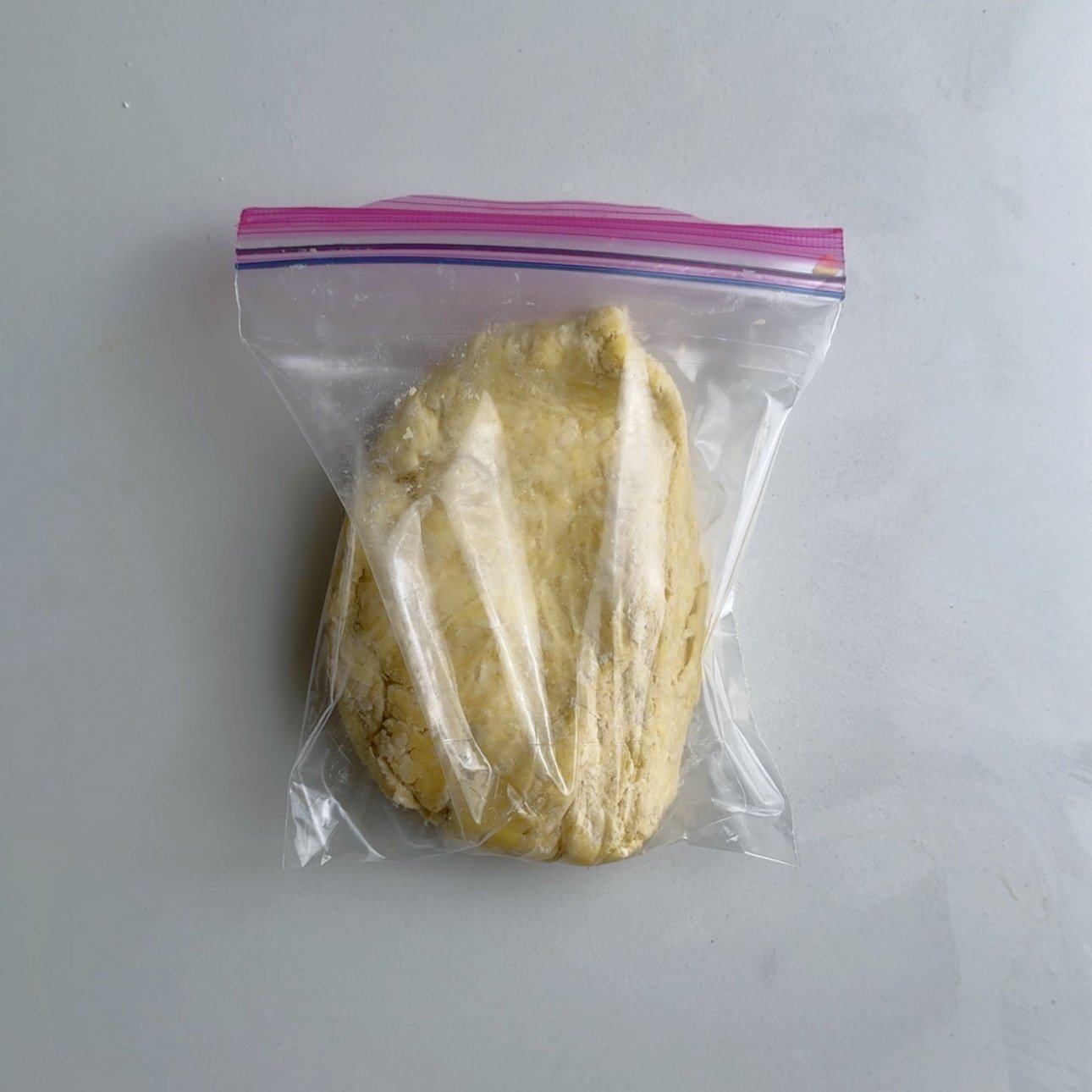 Guyanese pastry dough in a quart size ziplock plastic bag on a white surface