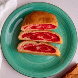 Slices of salara on a green plate with a white napkin to the left and a peek of the salara loaf to the right