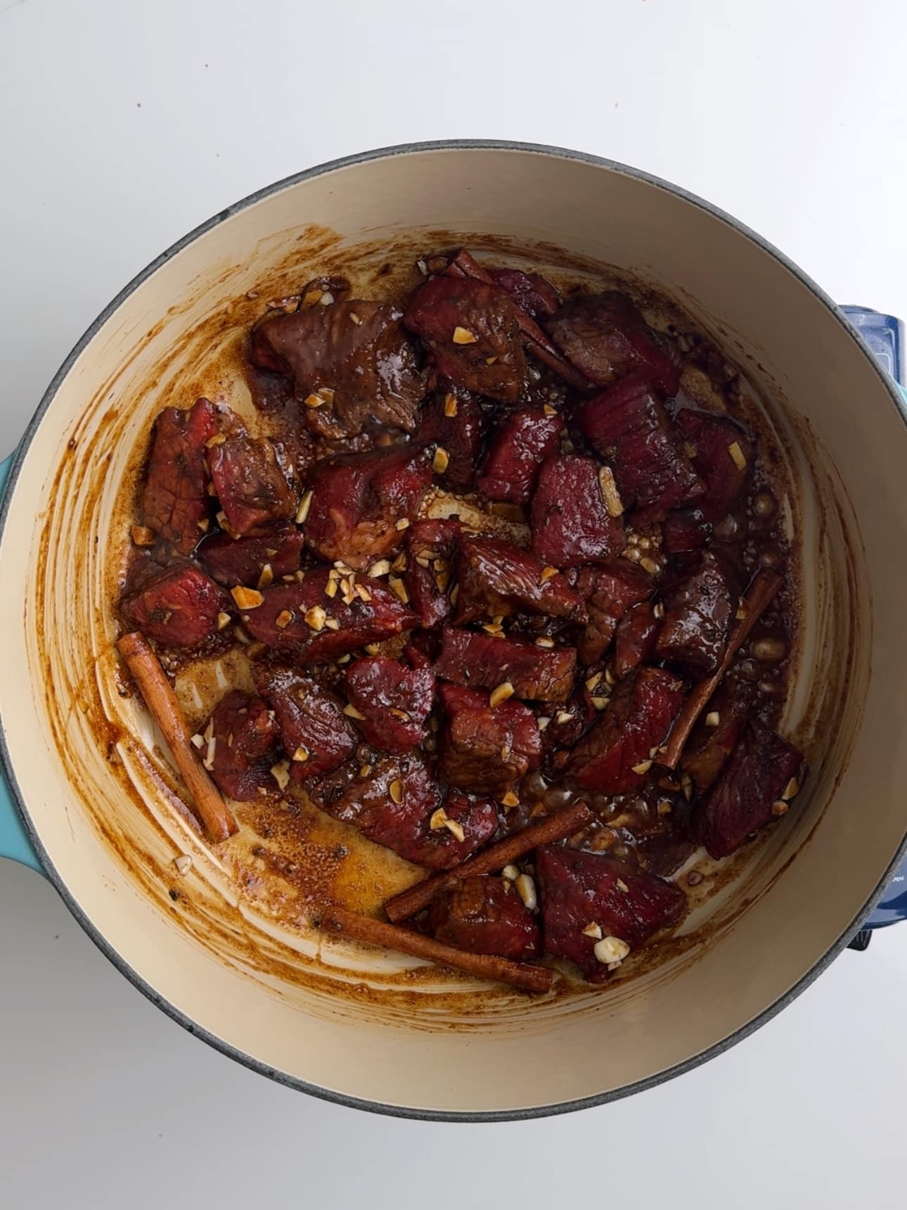 Chunks of beef sautéing in a stock pot as the beginning step for pepperpot