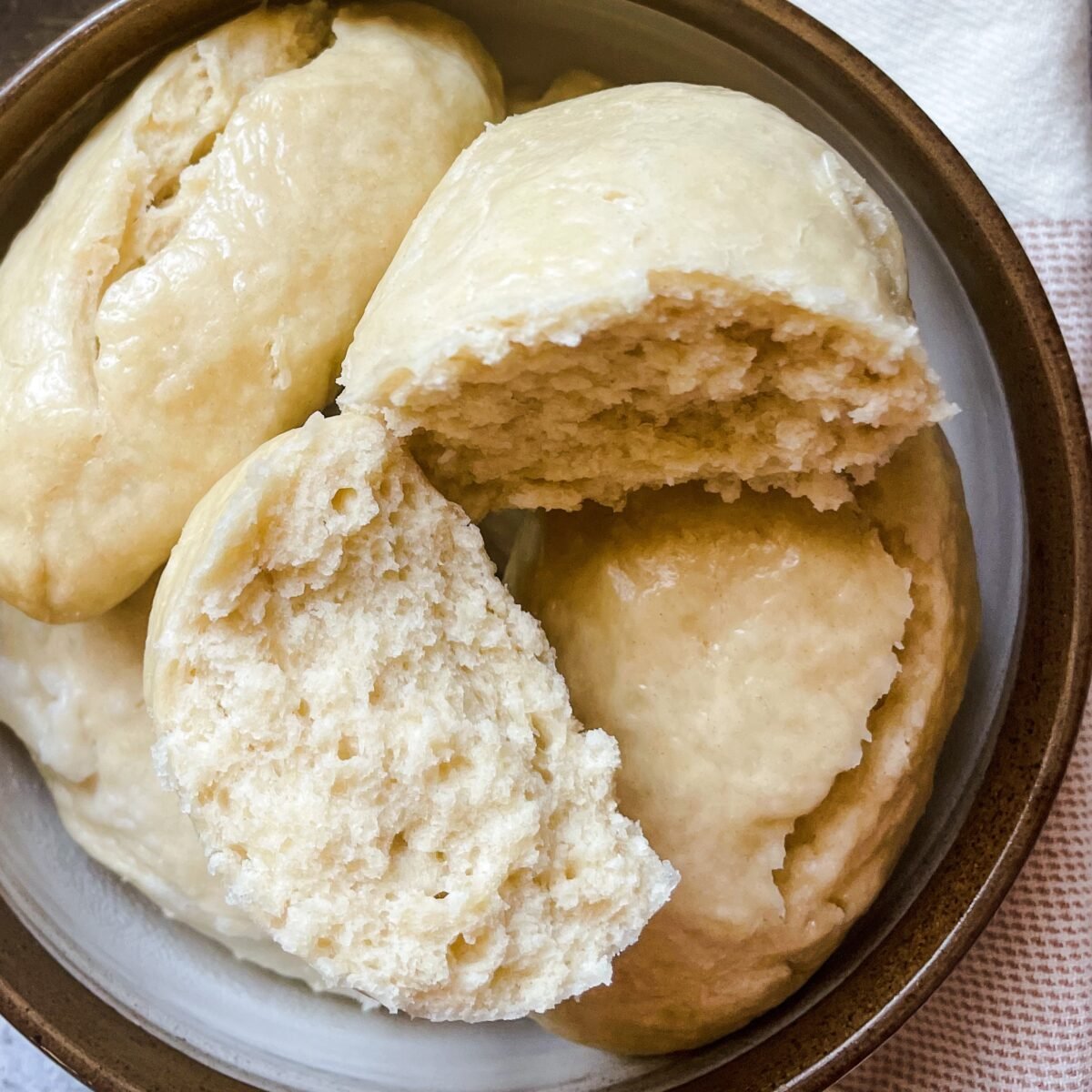 Several Guyanese Duff in a grey and brown bowl with one duff split in half showing a cross section of the duff.