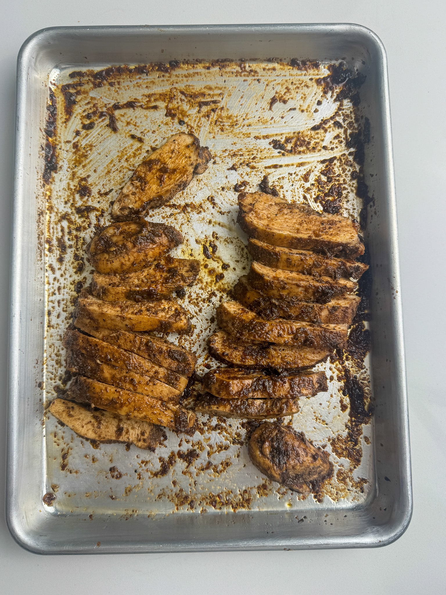 sliced jerk chicken breast on a baking sheet