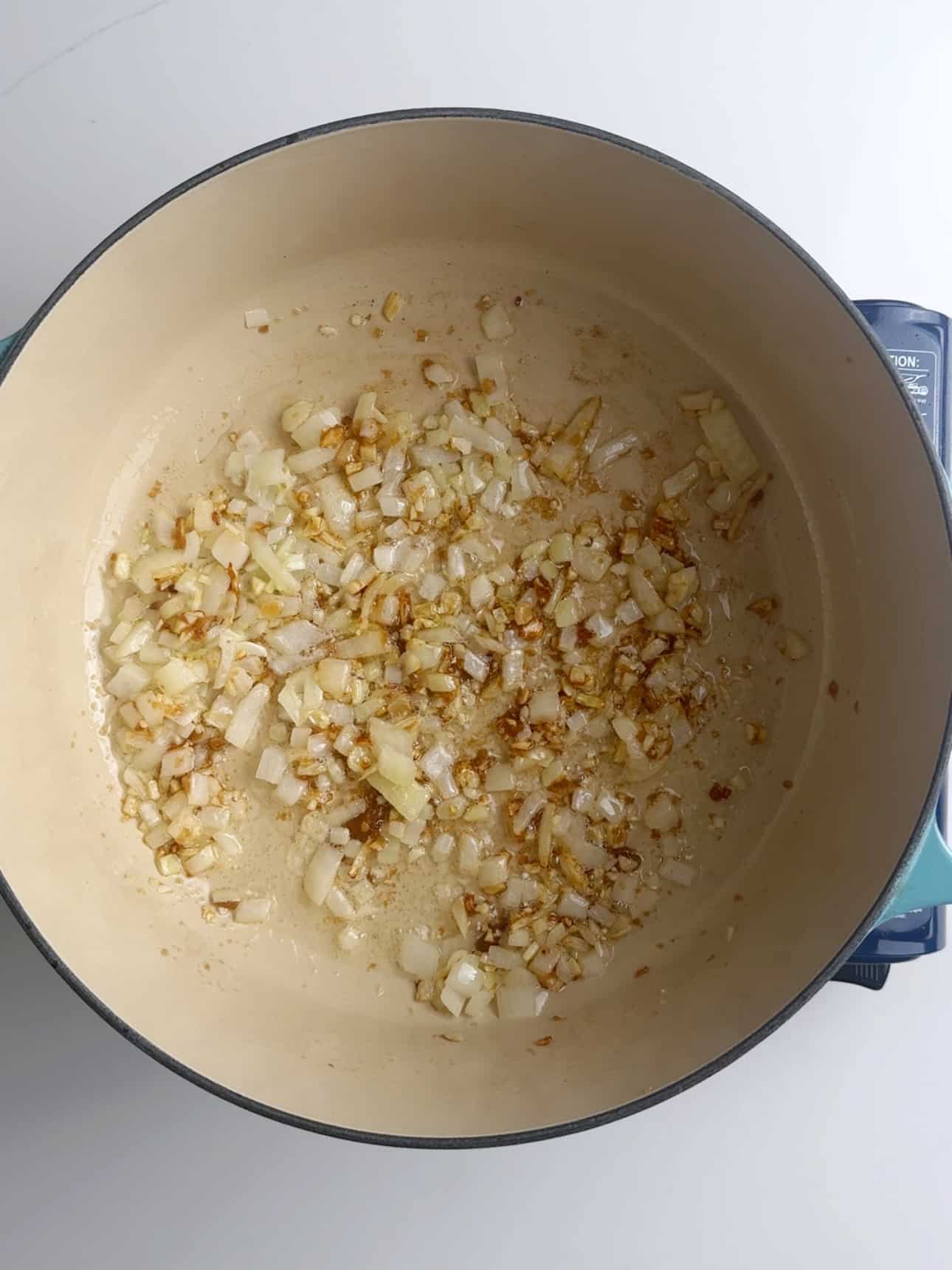 Onions, garlic and brown sugar simmering in a cream cast iron pot