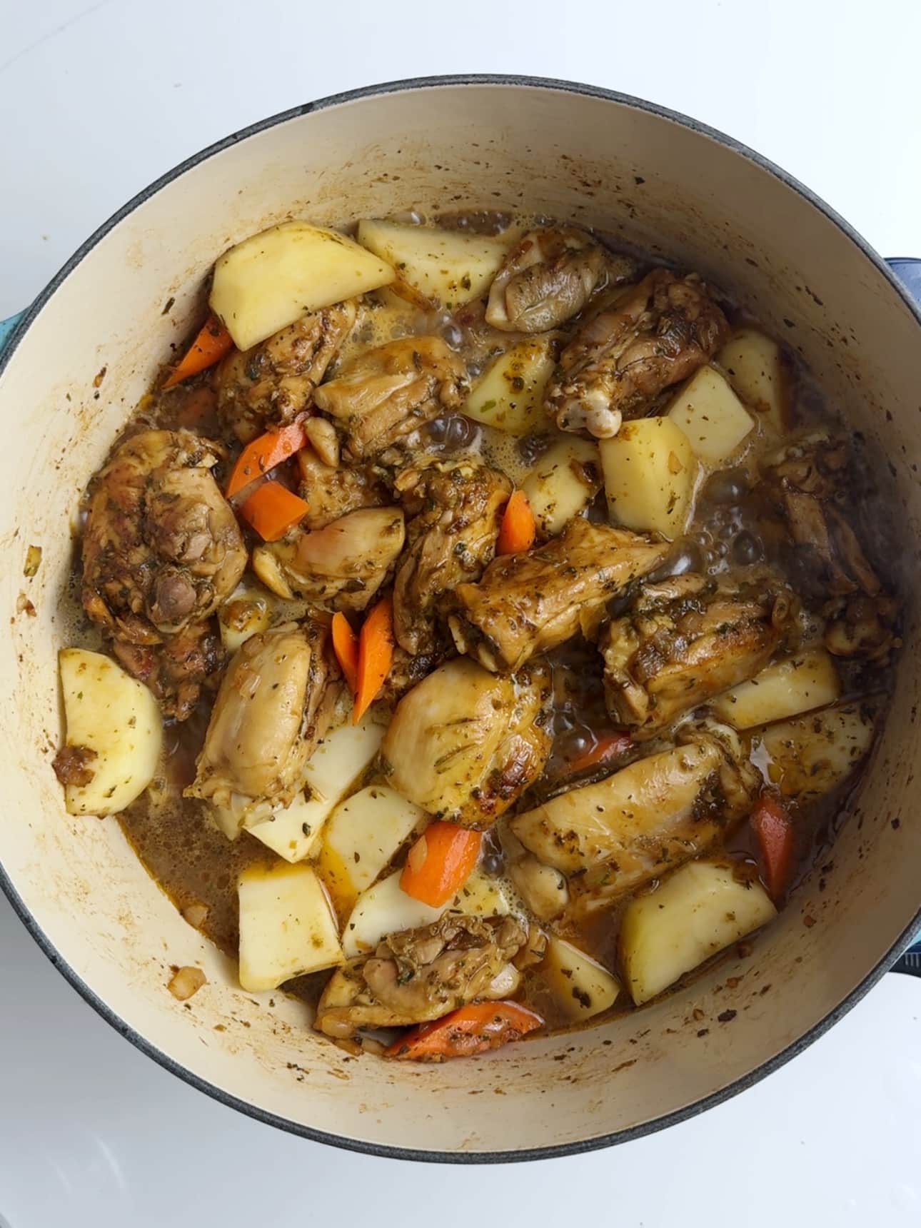 Ingredients for Guyanese Chicken stew in a large cast iron pot with visible liquid at the bottom of the stew. 