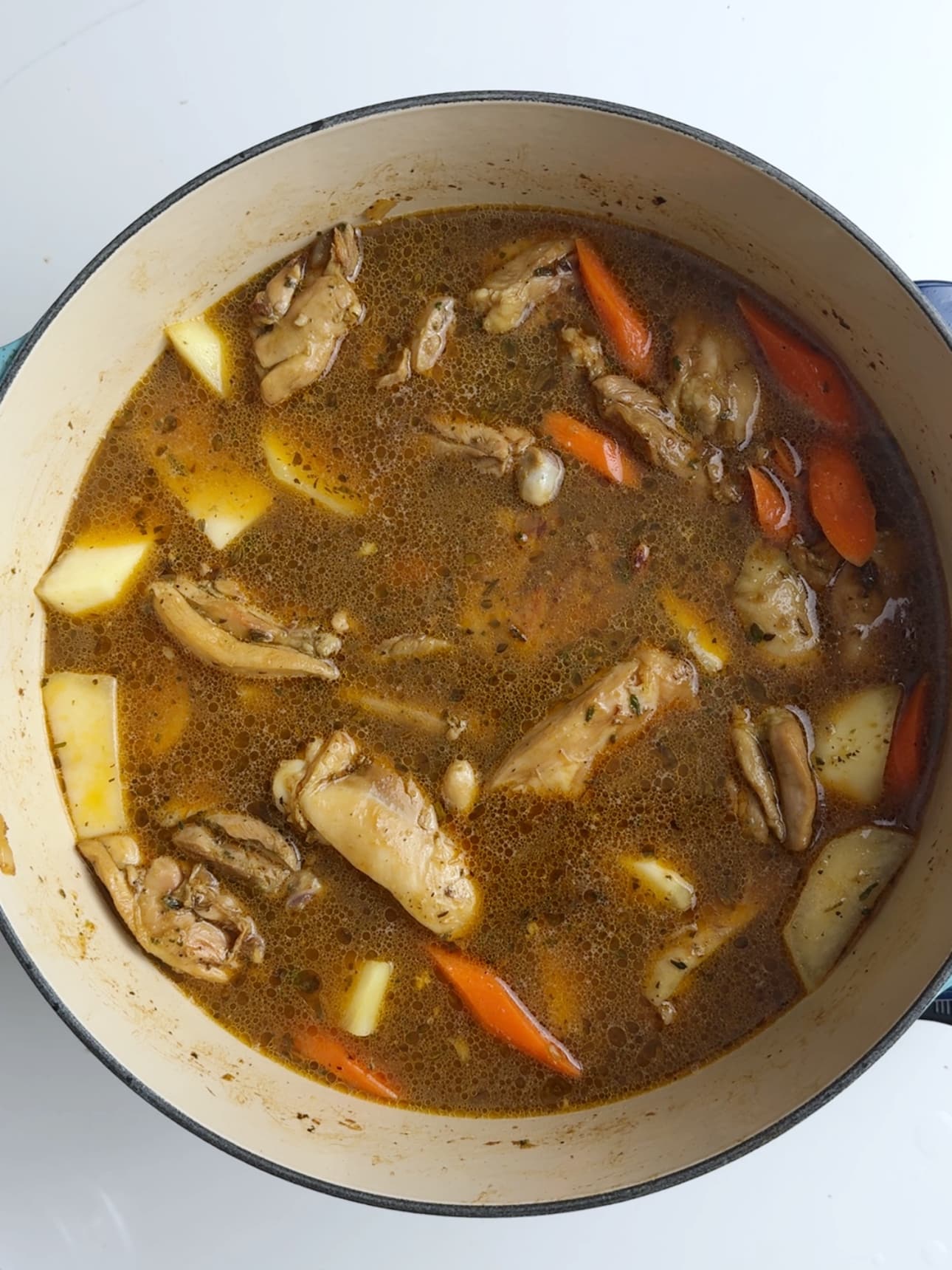 Guyanese stew chicken simmering in a large cast iron pot