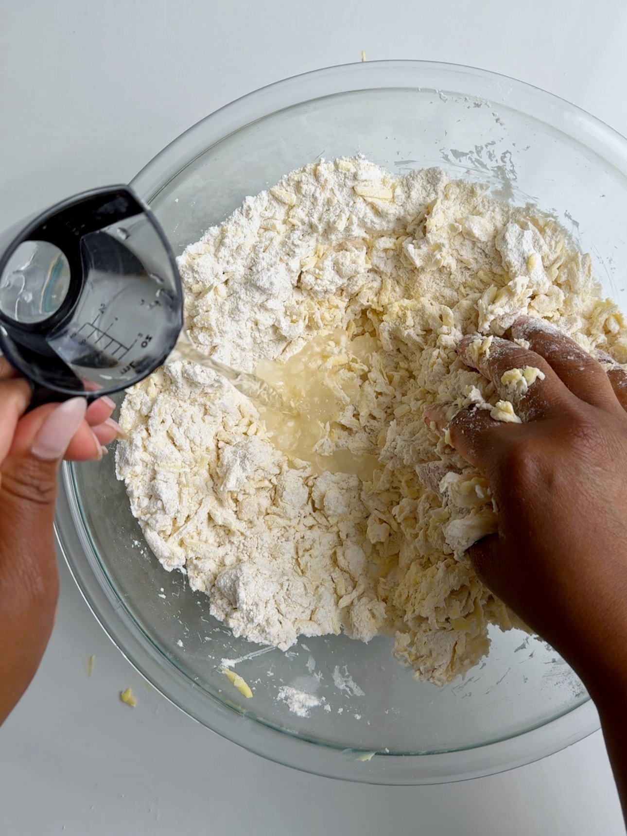 Pouring ice cold water into butter and flour to make pastry dough.