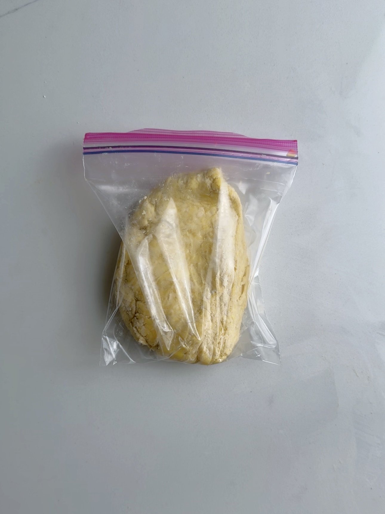 Pastry dough in a ziptop plastic bag on a white surface