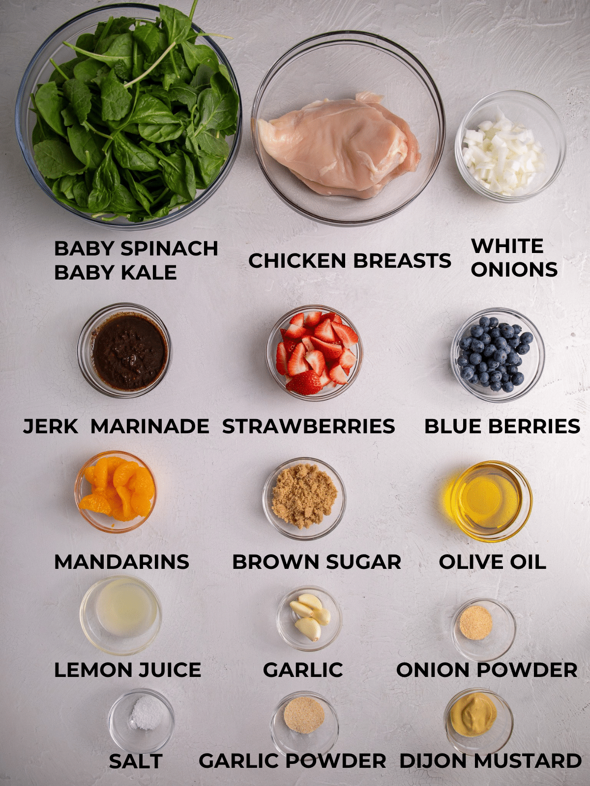 ingredients for jerk chicken salad including chicken breasts, greens, berries and jerk marinade
