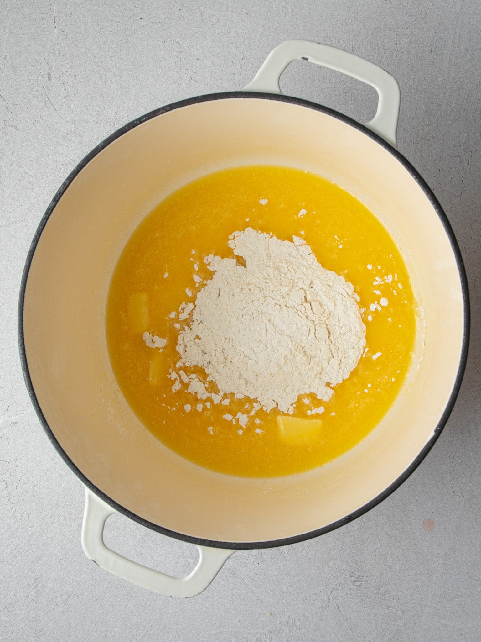 Flour added to melted butter in a cream Dutch oven to make a roux