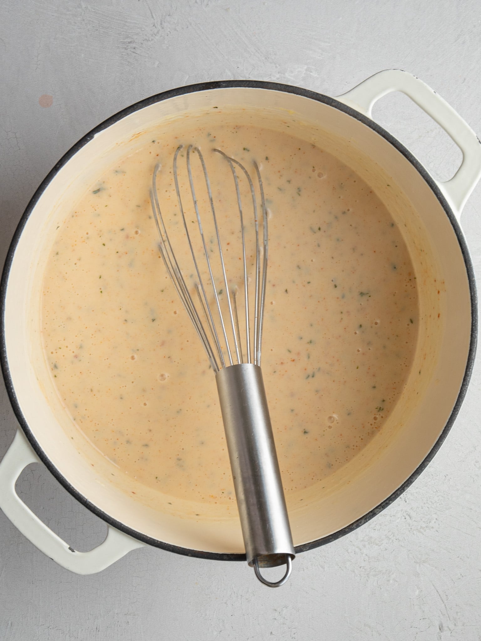 Seasoned béchamel sauce whisked smooth in a Dutch oven