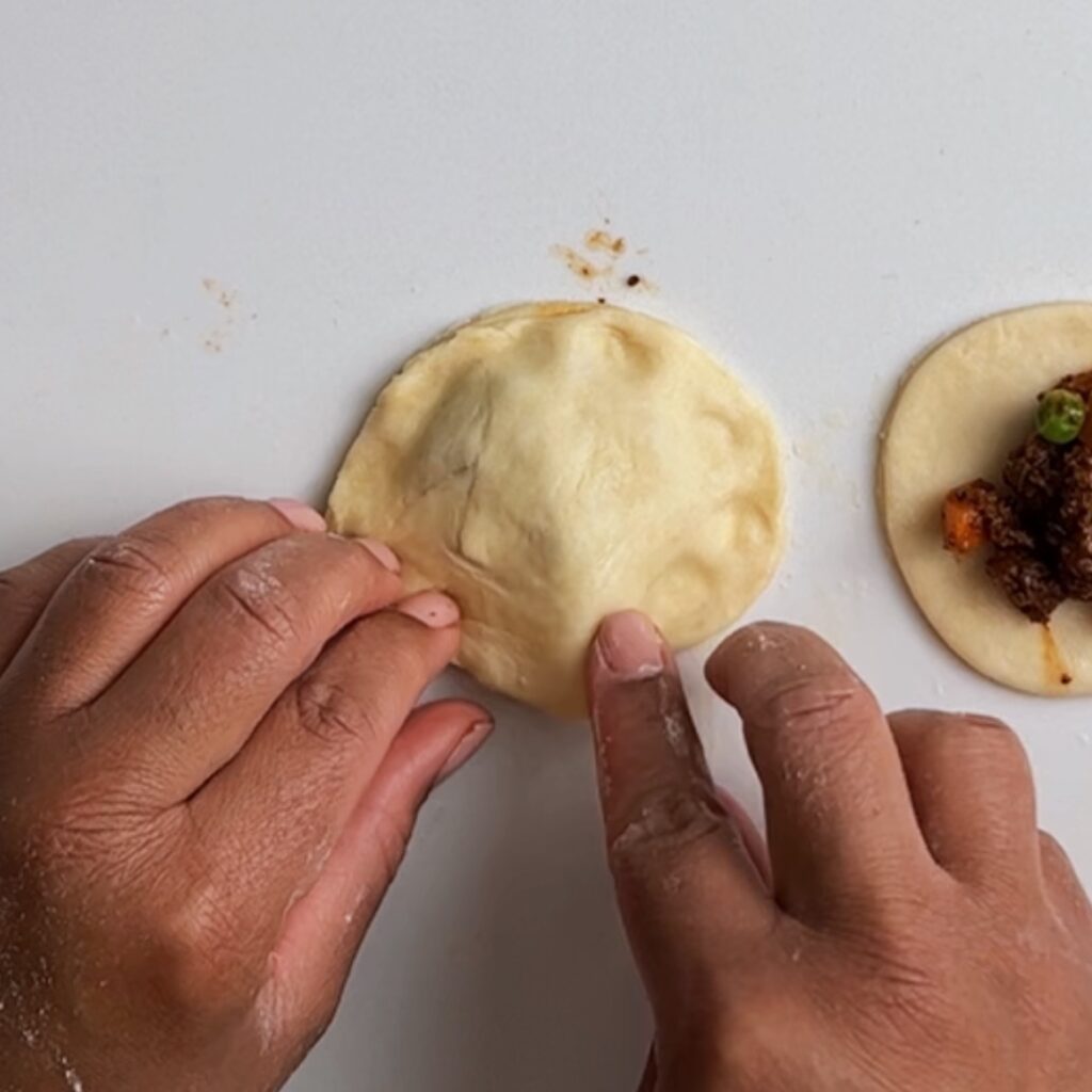 fingers pressing the Guyanese beef patties dough together