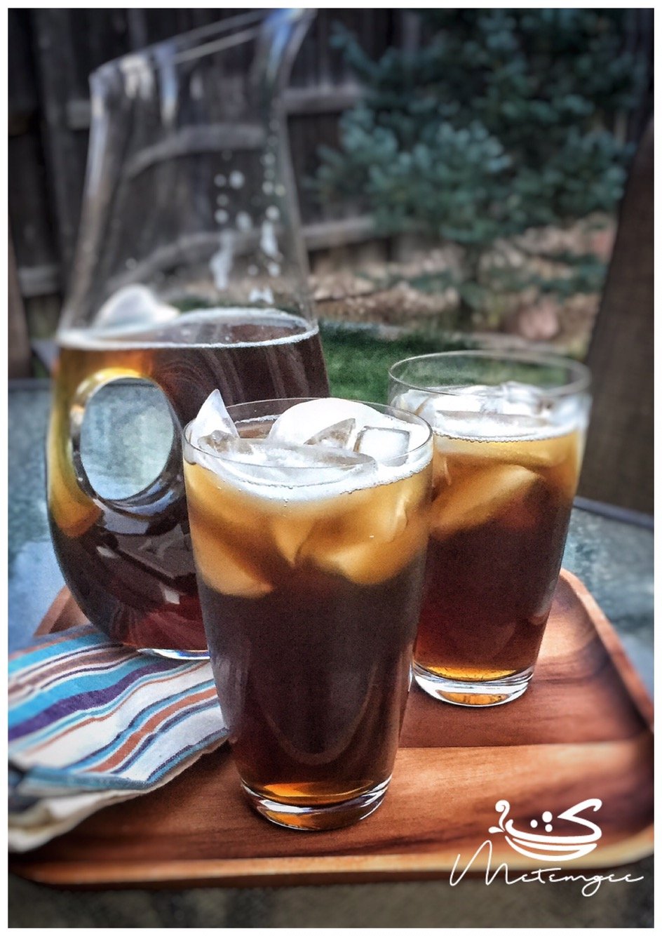 a pitcher of mauby with two glasses full in front of it