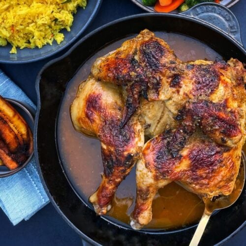 Roasted spatchcocked chicken in a skillet, with peeks of sides