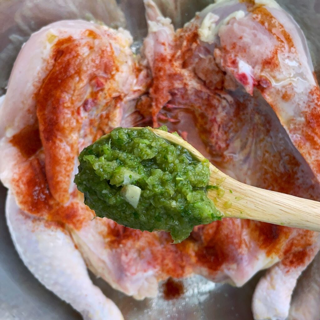 Spoonful of green seasoning over a spatchcock chicken